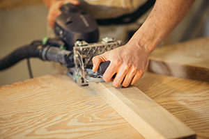 Carpenter planing timber in light workshop
